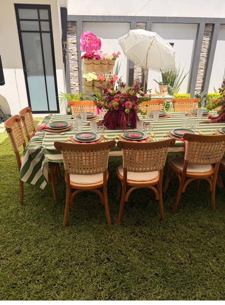 Montaje de mesa con mantelería a rayas verdes y centro floral en tonos vino